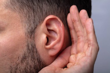 Close-up Of A Man Trying To Hear With Hand Over Ear clipart