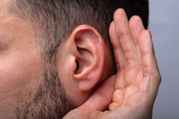 Close-up Of A Man Trying To Hear With Hand Over Ear