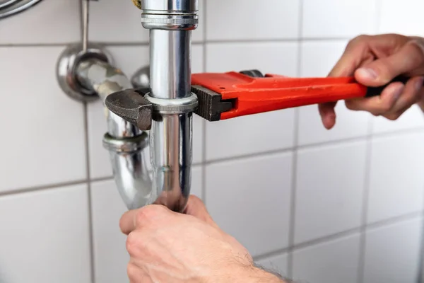 水管工用可调节扳手的手修复水槽的特写 — 图库照片