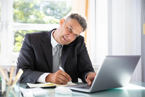 Empresário Conversando Celular Usando Laptop Enquanto Escreve Agenda Diário — Fotografia de Stock