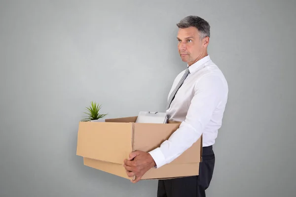 Side View Sad Businessman Carrying Belongings Cardboard Box Grey Background — Stock Photo, Image