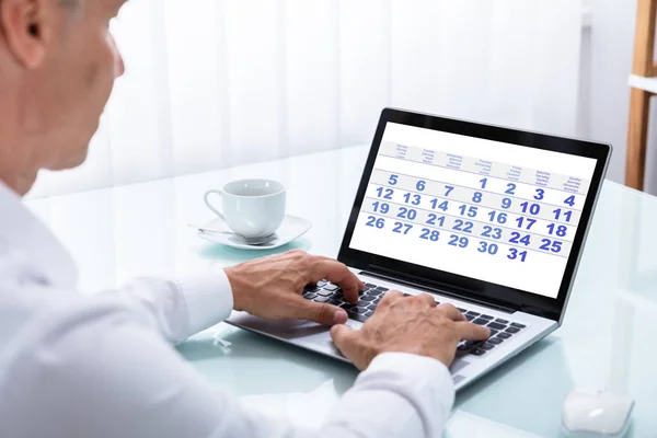 オフィスでラップトップのカレンダーを探しているビジネスマンのクローズ アップ — ストック写真