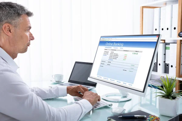 職場のコンピューターでオンライン バンキングを行うビジネスマンを成熟します — ストック写真