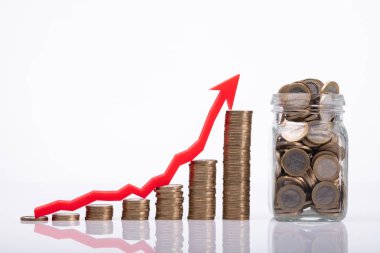 Kavanoz yığılmış sikke ve yukarı yön gösterilen kırmızı ok yanı sıra yakın çekim