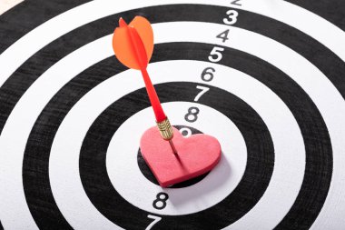 Kırmızı kalp şeklindeki dart tahtası üzerinde turuncu Dart oku Hits