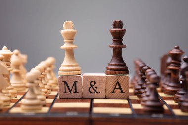 Close-up Of King Chess Pieces On Wooden Blocks With Mergers And Acquisitions clipart