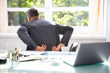 Ofiste sırt ağrısı muzdarip olgun bir işadamı yan görünüm
