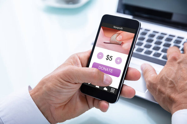 Close-up Of A Businessman's Hand Donating Money Online On Mobile Phone