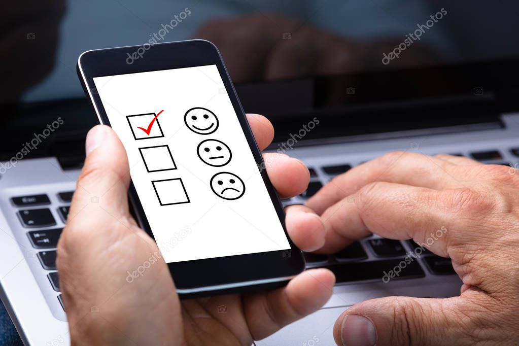 Close-up Of A Man's Hand Holding Smartphone With Ticked Checkbox And Smile Icon On Screen