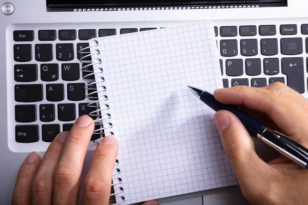 Personens Hand Skrivande Spiral Anteckningsblock Över Laptop Tangentbord — Stockfoto