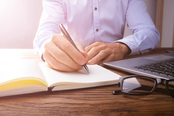 Personens Hand Skrivande Svart Anteckningsbok Med Penna Över Laptop — Stockfoto