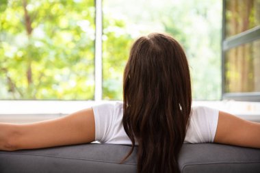 Koltuk pencerenin önünde oturan bir kadının arkadan görünüş