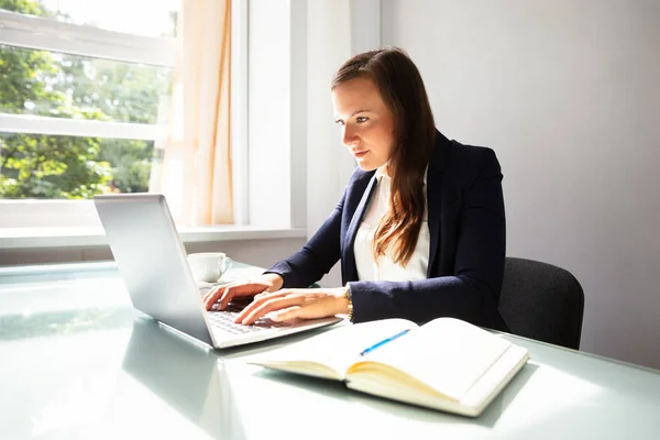 Junge Geschäftsfrau Tippt Auf Laptop Mit Tagebuch Auf Schreibtisch — Stockfoto