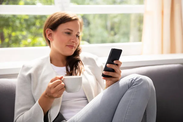 Mujer Joven Con Taza Café Usando Teléfono Móvil —  Fotos de Stock