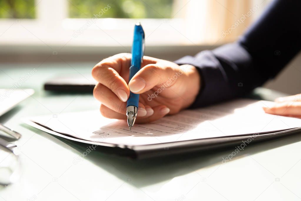 Close-up Of A Businesswoman's Hand Filling Contract Form