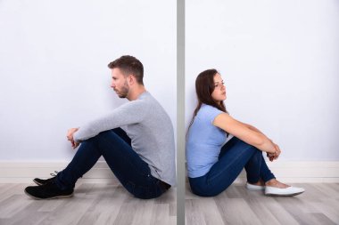 Mutsuz genç bir çift arka arkaya evde otururken yan görünüm