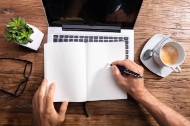 Adam yazma Laptop üzerinde boş not defteri üzerinde yükseltilmiş görünümü