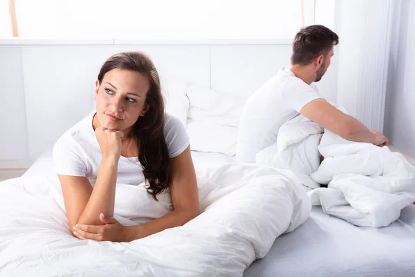 不开心的年轻夫妇坐在床上的卧室 — 图库照片