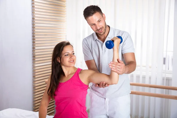 Male Therapist Assisting Young Female Patient While Exercising Dumbbell — Stock Photo, Image