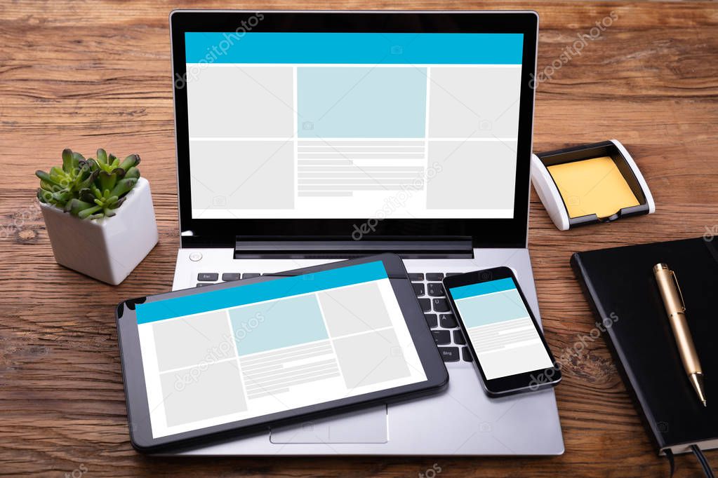 Electronic Devices With Screen On Wooden Desk Near Diary And Pen