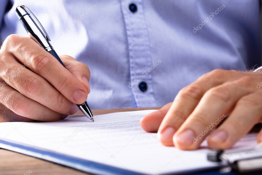 Close-up Of A Businessman's Hand Signing Contract Papers