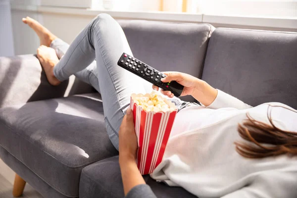 Žena Ležící Pohovce Drží Dálkové Ovládání Televize Popcorn — Stock fotografie