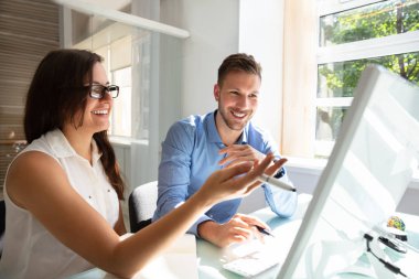 İşyerinde konuşmayı bilgisayar bakarak iki profesyonel genç iş adamları