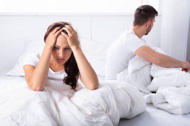 Mutsuz genç çift yatak yatak odasında oturup...