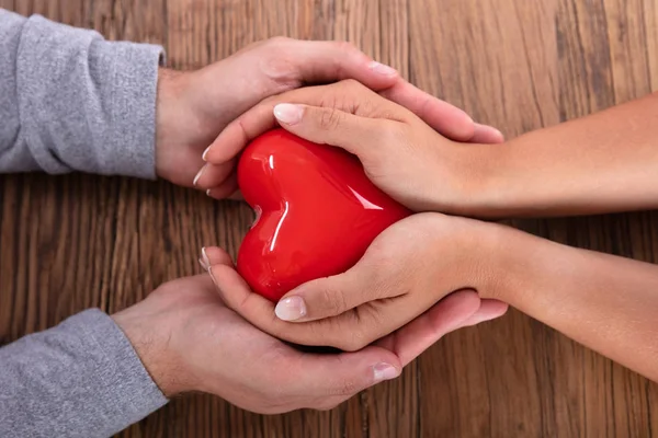 Pareja Sosteniendo Corazón Rojo Sobre Fondo Madera —  Fotos de Stock