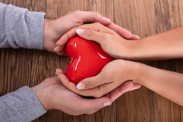 Coppia Tenendo Cuore Rosso Sfondo Legno — Foto Stock