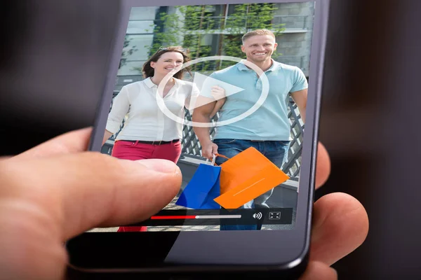 手持手机与屏幕上的视频的人的手 — 图库照片