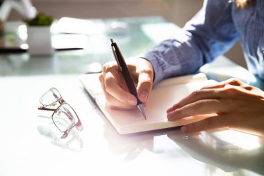 Bir iş kadını'nın el yazma notlar gözlük üstünde okul sırası ile Not defterinizdeki Close-up