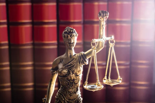 红色法律书籍面前的金色正义雕像 — 图库照片