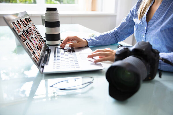 Редактор Ретуширование фотографий на ноутбуке с DSLR камерой на столе
