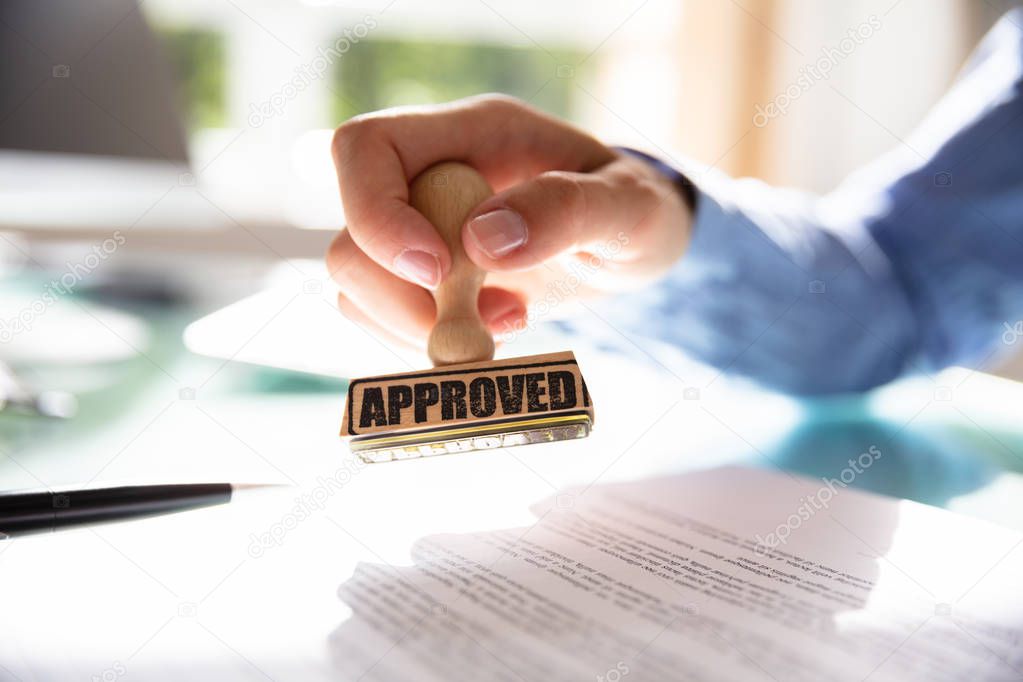 Close-up Of A Businesswoman's Hand Stamping On Approved Contract Form