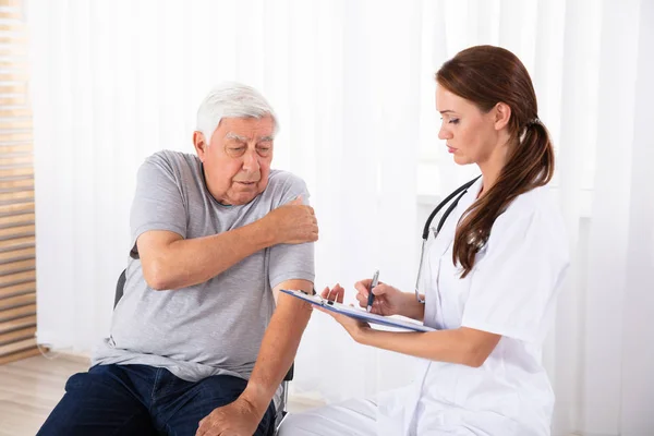 Junge Ärztin Verschreibt Älteren Männlichen Patienten Mit Armschmerzen — Stockfoto
