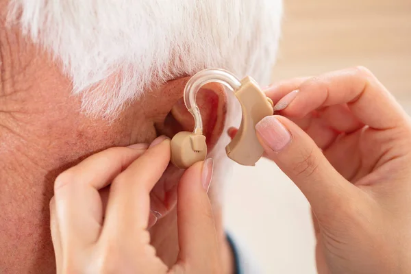 Female Doctor Hand Inserting Hearing Aid Senior Male Patient Ear — Stock Photo, Image