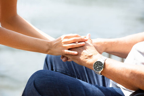 Close-up Of A Woman Holding Her Father's Hand At Outdoors