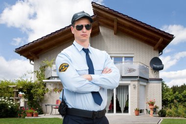 Erkek güvenlik görevlisi evin önünde duran güneş gözlüğü takıyor