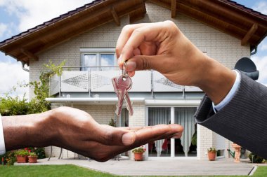 Close-up Of Real Estate Agent Giving Key To Client In Front Of House clipart