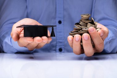 Mezuniyet şapka ve paralar Danışma üzerinde tutan bir kişinin el Close-up