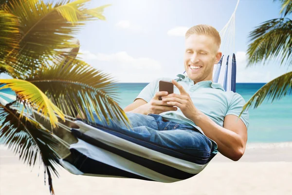 Šťastný Mladý Muž Relaxaci Houpací Síti Pomocí Smartphonu — Stock fotografie