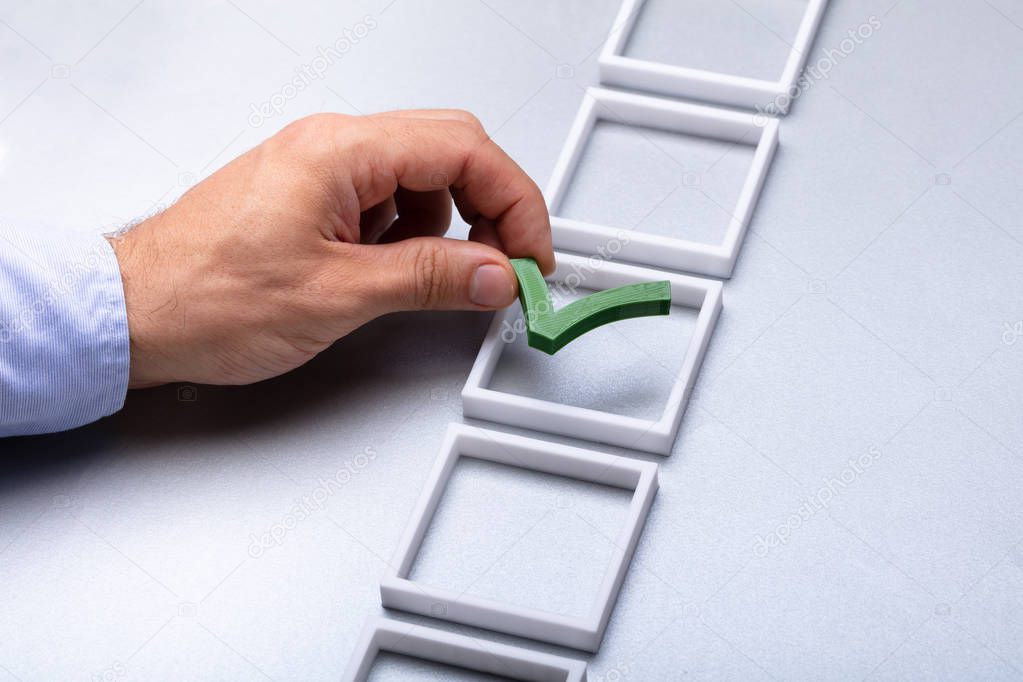 Man's Hand Placing Green Check Mark In Box On Grey Background