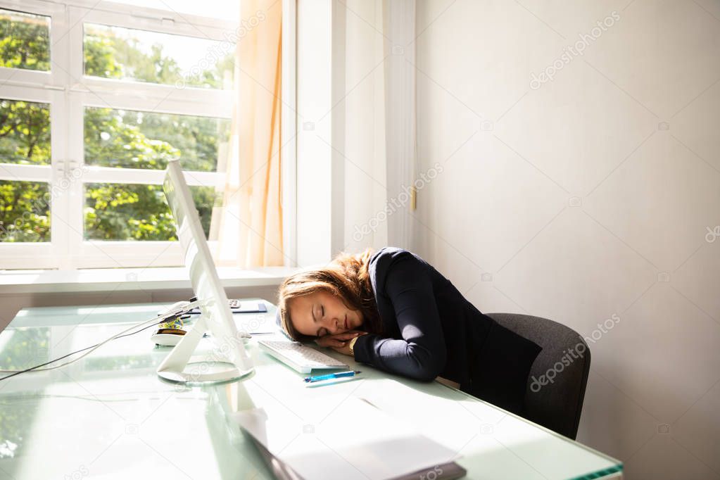 Close-up Of A Young Businesswoman Sleeping Over Desk