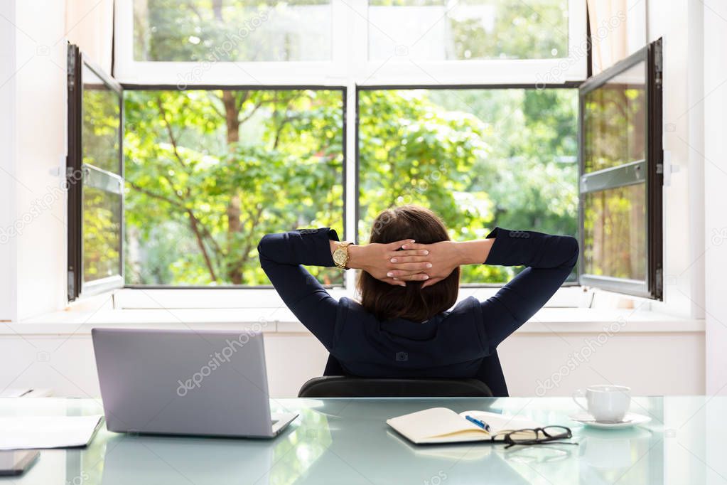 Relaxed Businesswoman With Hands Behind Head Sitting In Office
