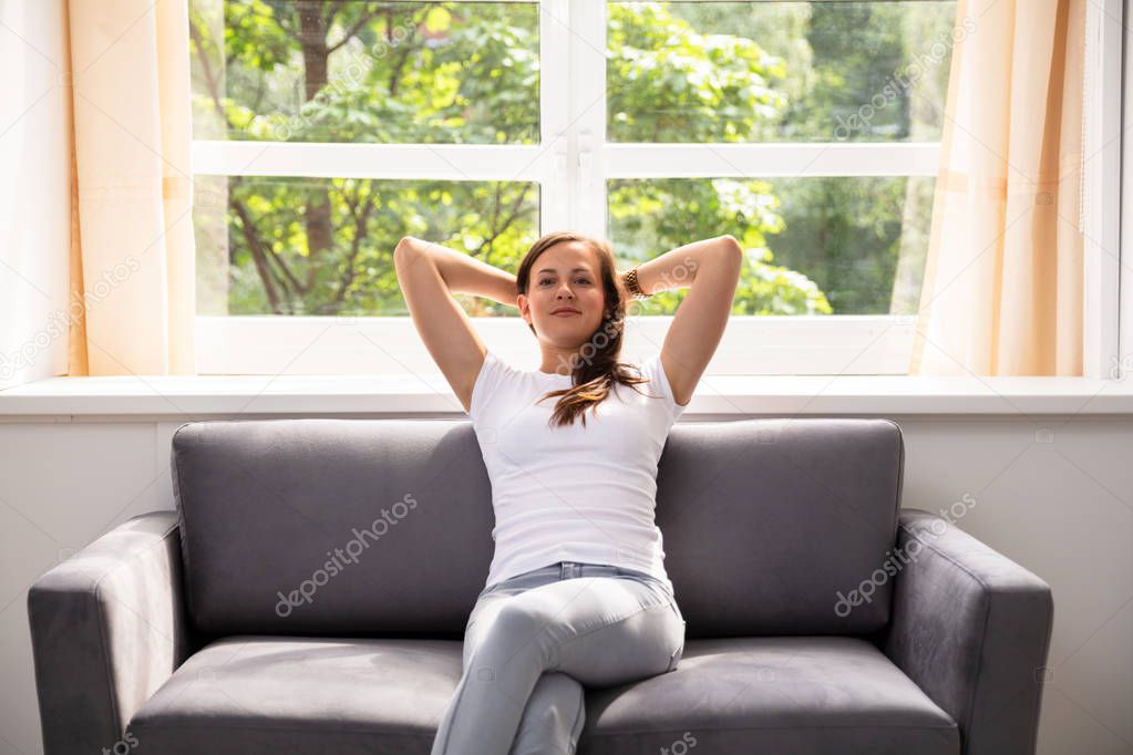 Portrait Of A Relaxed Woman Sitting On Sofa