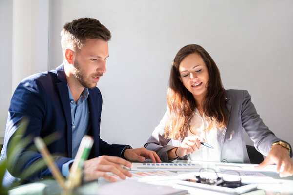 Два молодых бизнесмена анализируют график на рабочем столе
