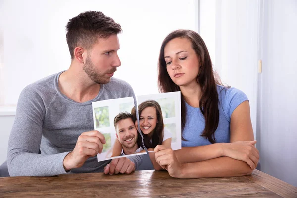 Triste Pareja Joven Sosteniendo Fotografía Desgarrada Sobre Escritorio Madera — Foto de Stock