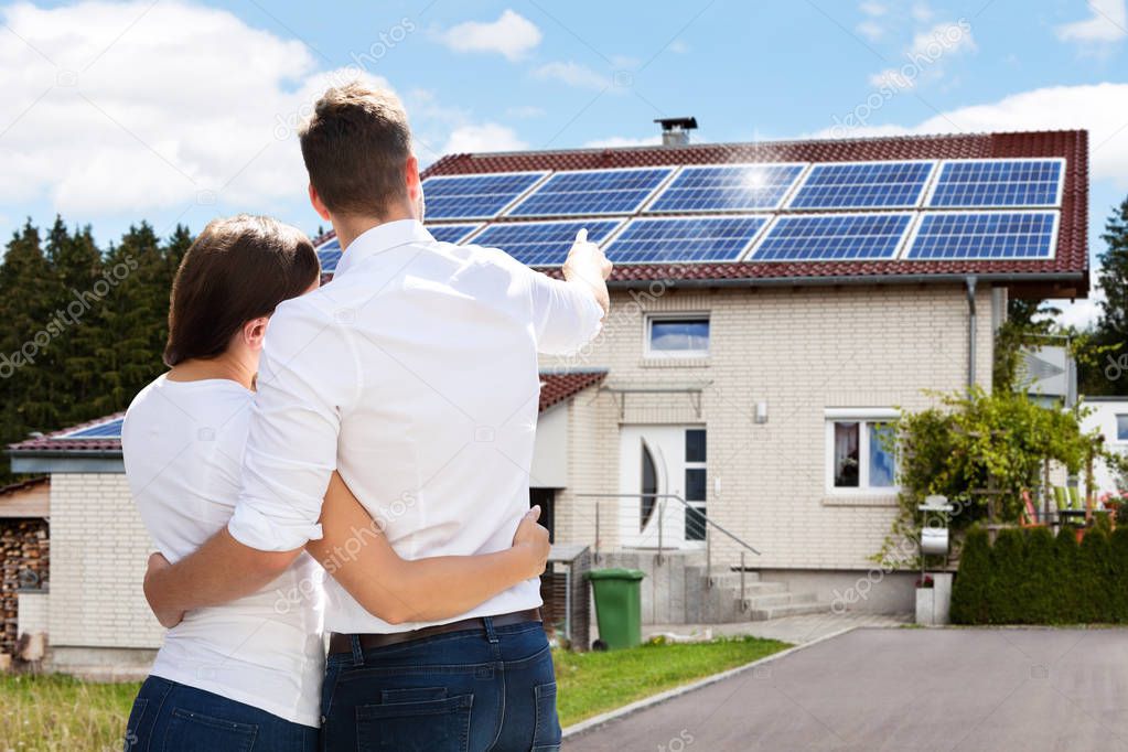 Rear View Of A Young Couple Standing In Front Of Their New House