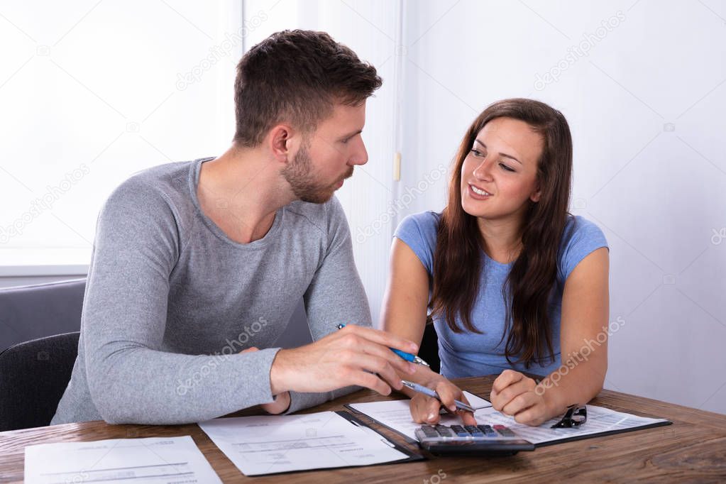 Young Couple Having Conversation While Calculating Invoice